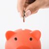 豚の貯金箱に小銭を入れる